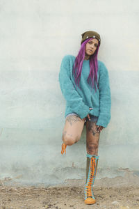 Portrait of young woman standing against wall