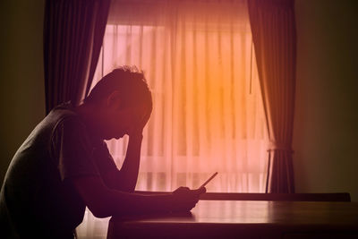 Side view of a man sitting on table at home