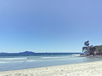 View of calm beach against clear blue sky