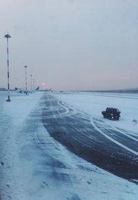 Snow covered road against sky during winter