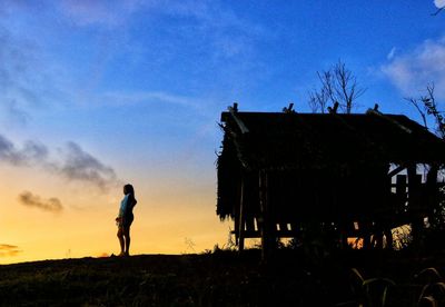 Silhouette man standing on field against sky during sunset