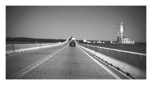 Rear view of woman walking on road against clear sky