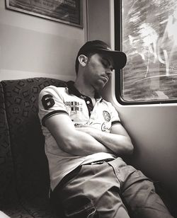 Side view of young man sitting by window