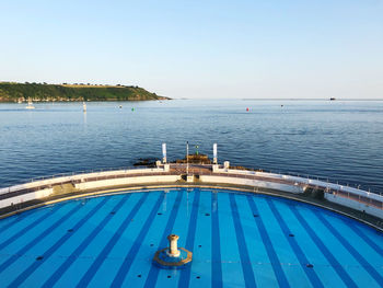 Scenic view of swimming pool by sea against clear sky