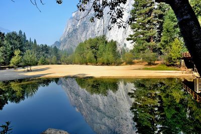 Reflection of trees and steep mountain in calm lake