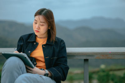 Asian woman use tablet for stock and cryptocurrency trading from outdoor of coffee shop