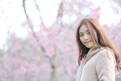 Portrait of beautiful young woman standing against blurred background