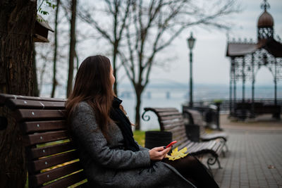 Side view of woman sitting on bench