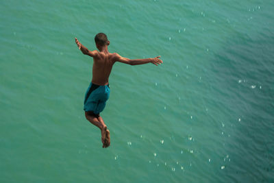 Full length of shirtless man jumping in sea