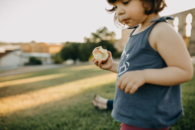 Boy holding ice cream standing on field