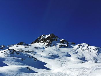 Low angle view of snowcapped mountain against clear blue sky