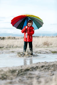 Full length of woman standing on wet road during rainy season