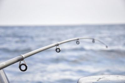 Close-up of metal against sea against clear sky