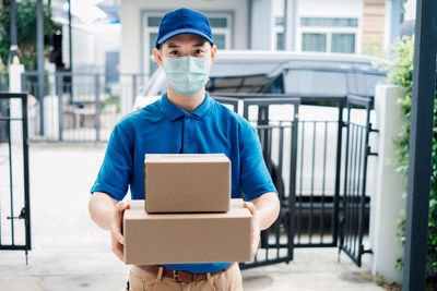 Portrait of man holding camera while standing in box