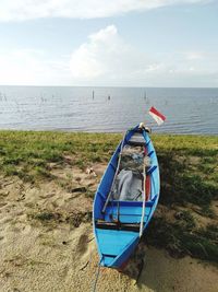 Boat on the grass by the beach with a flag at its stern