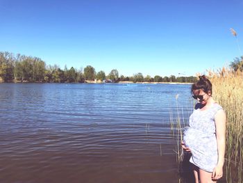 Woman standing in lake against clear sky