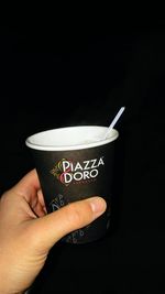 Man holding coffee cup against black background