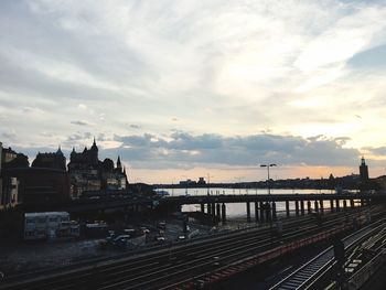 Bridge over river in city against sky during sunset