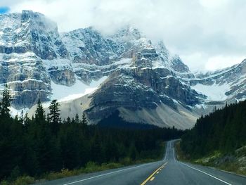 Road amidst snowcapped mountains against sky