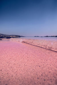 Surface level of beach against clear blue sky