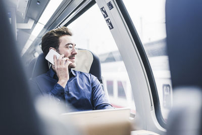 Smiling businessman in train on cell phone