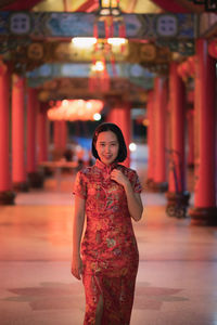 Portrait of woman standing against red wall