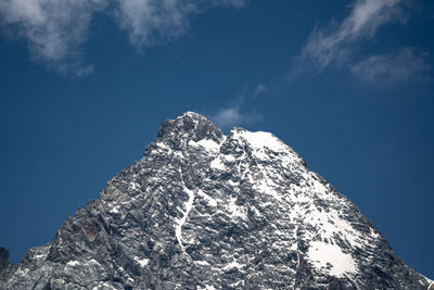 Low angle view of snowcapped mountain against blue sky