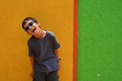 Happy boy laughing against wall