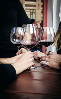 Midsection of woman holding wine glass on table