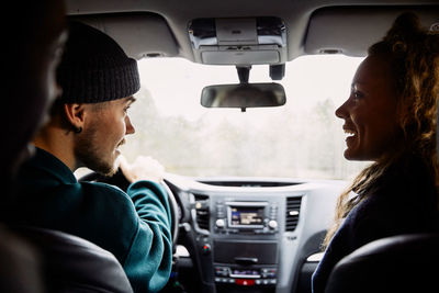 Male and female friends talking while traveling in car