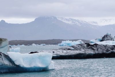 Scenic view of sea and snowcapped mountains against sky