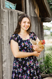 Cute woman holding chicken in countryside