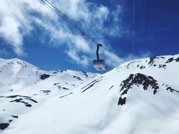 Low angle view of snow covered mountains against blue sky