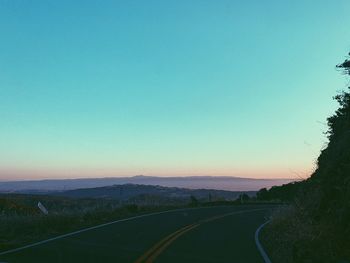 Road amidst landscape against clear blue sky