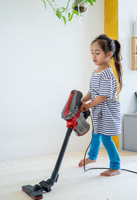 Cute little girl cleaning wooden floor with vacuum cleaner