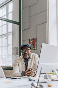 Portrait of businessman with hands intertwined at work place