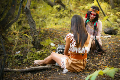 Women sitting with raccoon in forest