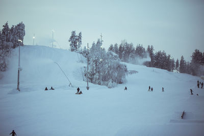 People skiing and snowboarding on snow covered land