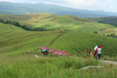 People on grassy field against mountains