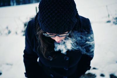 Close-up of woman smoking while standing on snow