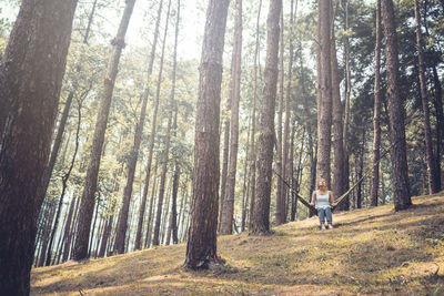 Woman sitting on hammock in forest