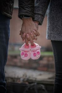 Midsection of couple holding baby booties 