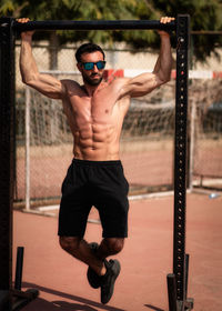 Full length of shirtless man exercising outdoors