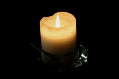 Close-up of illuminated tea light candle in darkroom