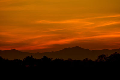 Scenic view of silhouette mountains against orange sky