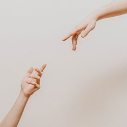 Cropped hand of woman gesturing against wall