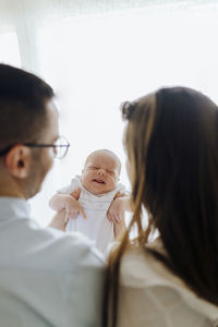 Mother and father from behind holding their newborn son gesturing. new parents