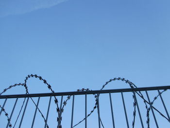 Low angle view of barbed wire against clear blue sky