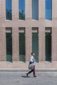 Full length of man walking on street against building