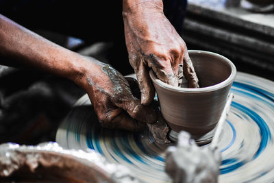 Cropped hands of man making pot in workshop